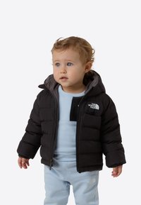 Czarna kurtka puchowa z szarym wnętrzem i kapturem, wyposażona w przedni zamek błyskawiczny oraz logo. Do kompletu jasnoniebieska bluza i spodnie.