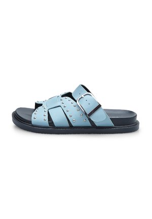 Light blue leather sandals with a cross-strap design, silver studs, and a prominent buckle. Black rubber sole with a textured finish.