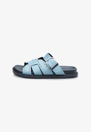 Lichtblauwe leren sandalen met een kruisbandontwerp, zilveren studs en een opvallende gesp. Zwarte rubberen zool met een gestructureerde afwerking.