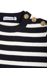 Maglione a righe bianche e nere con colletto a coste, caratterizzato da tre bottoni dorati decorati con ancore sulla spalla e un'etichetta di tessuto.