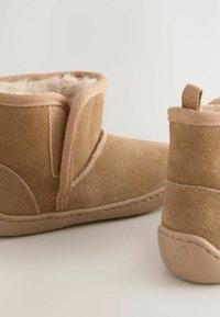 Beige Wildlederschnürstiefel mit weichem Fleece-Futter, featuring einem gestickten Design und einer Gummisohle mit einem Bärenlogo an der Ferse.