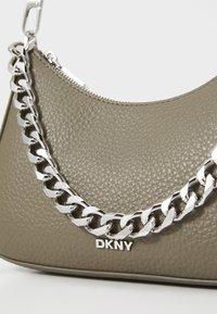 Oljčnozelena usnjena torbica z teksturiranim zaključkom, ki ima srebrno verigo in DKNY logotip na dnu. Zadrga na vrhu.