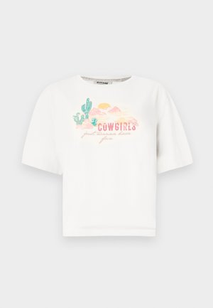 Biela bavlnená tričko s krátkymi rukávmi, na ktorom je farebná grafika púšte a text "COWGIRLS len chcú zabávať" v ružovej a zelenej farbe.