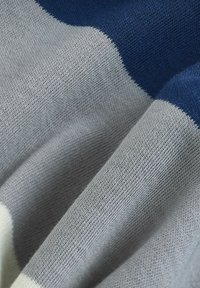 Gebreide trui met afwisselend blauwe, grijze en crèmekleurige strepen; zachte textuur en fijne stiksels in close-up zichtbaar.