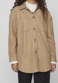 Braun melierte Wollmischung-Übershirt mit Knopfverschluss, zwei Brusttaschen und lockerer Passform. Mit spitzem Kragen und strukturiertem Stoff.