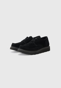 Scarpe in suede nero con suola in gomma spessa, punta rotonda e design classico con lacci. Presentano cuciture a contrasto lungo la suola.