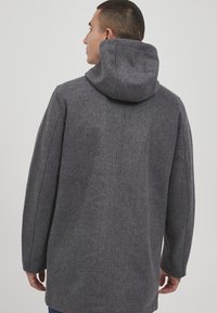 Grau melierter Wollmantel mit Kapuze, gerader Silhouette und Nahtdetails auf dem Rücken. Weiche Textur, entworfen für Wärme.