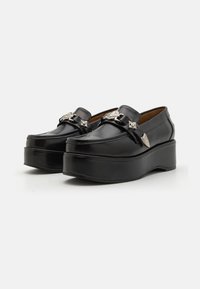 Loafers negri cu platformă, confecționați din piele lucioasă, cu accente decorative argintii și vârf rotunjit. Talpă înălțată pentru un plus de înălțime.