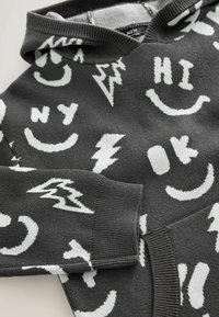 Gray knit hoodie featuring white graphic patterns such as smiley faces, lightning bolts, and text elements. Ribbed cuffs and hood.