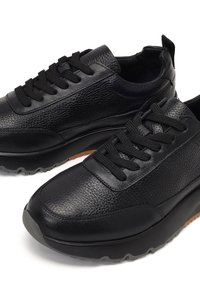 Zwarte sneakers van gestructureerd leer met rubberen zolen, voorzien van ronde neuzen, platte veters en een gewatteerde kraag voor comfort.