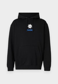 Black hoodie with a front kangaroo pocket, featuring a white and blue HUF and Kodak logo on the chest. Made from soft fabric.
