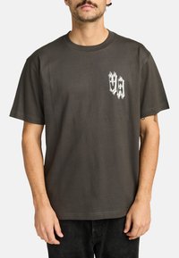 Donkergrijze katoenen T-shirt met een ronde hals, korte mouwen en een witte grafische print op de linkerborst met gestileerde letters.
