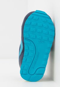 Nike-sko med marinblå ovandel, ljusblå detaljer och en texturerad gummisula för grepp, placerad mot en vit bakgrund.