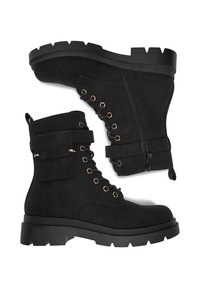 Černé kotníkové boty vyrobené z texturovaného umělého jemného semiše, se zlatými kroužky, bočním zipem a robustní masivní podrážkou.