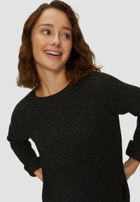 Zwart gebreid sweater met een ronde halslijn, ribbelmanchetten en een textuurpatroon, met een relaxte pasvorm en een zachte uitstraling.