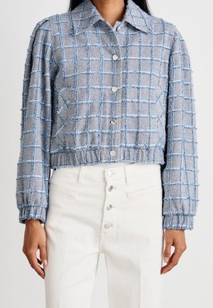 Blauw-grijs getextureerd geruit cropped blousejasje met lange mouwen, gecombineerd met hoog getailleerde witte broek met knoopsluiting.