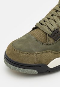 Olivově zelené tenisky s semišovým a strukturovaným svrškem, kulatou špičkou, černou gumovou podrážkou a vzorovanými akcenty. Masivní šňůrky a detaily na šití.