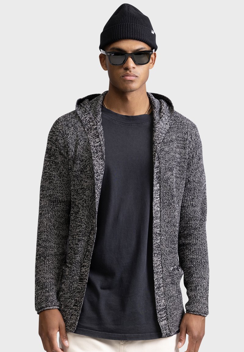 Black and gray knit hooded cardigan with open front, textured fabric, long sleeves, and side pockets, layered over a black shirt.