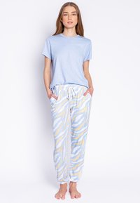 Lichtblauw T-shirt met korte mouwen, gecombineerd met gemêleerde joggingsbroek met gele en witte zigzagpatronen en stippen; elastische tailleband.