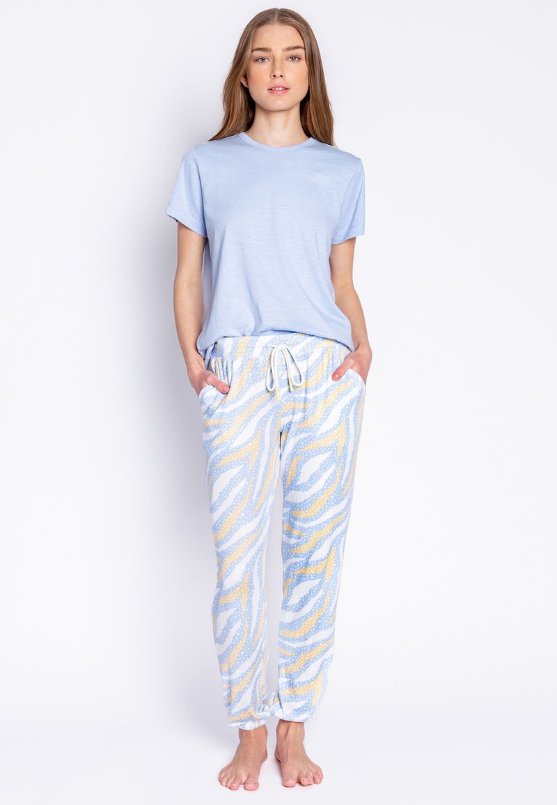 Lichtblauw T-shirt met korte mouwen, gecombineerd met gemêleerde joggingsbroek met gele en witte zigzagpatronen en stippen; elastische tailleband.