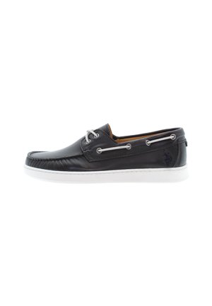 Schwarze Lederbootsschuhe mit weißer Gummisohle, klassischem Schnürsystem, strukturiertem Stich und kleinem Logodetail an der Seite.