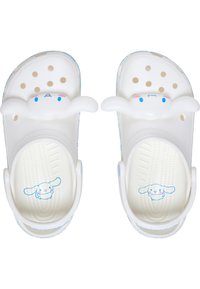 White sandals with a textured base, featuring polka dots and a large grey bunny design on the strap, with blue and pink accents.