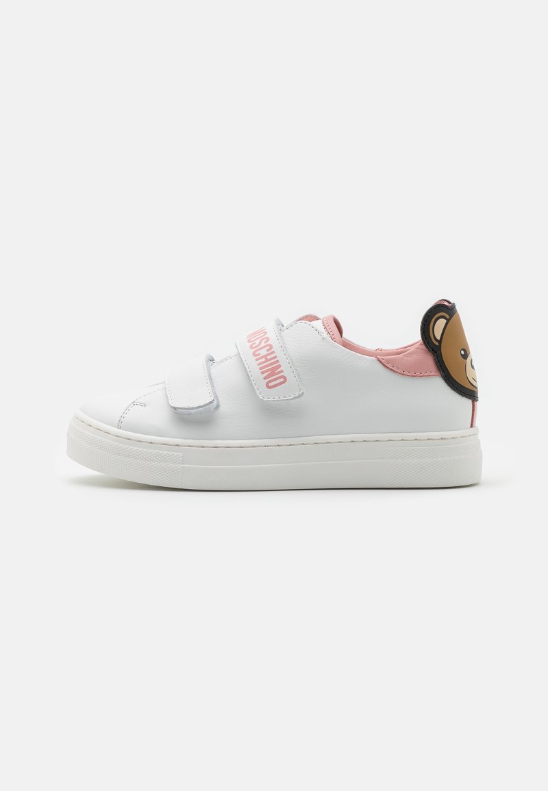 Zapatillas de cuero blanco con acentos en rosa, correas de Velcro y un diseño de oso en el talón. Cuentan con una suela texturizada para un mejor agarre.