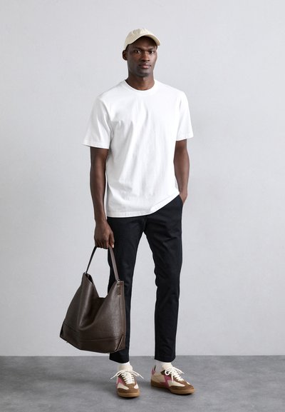 Bolso tote de cuero marrón, camiseta de algodón blanca, pantalones negros ajustados, gorra beige y zapatillas con acentos en rosa, blanco y beige.