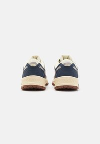 Baskets de sport bleu et crème avec une tige en tissu texturé, semelles en caoutchouc, talon renforcé et semelle à motifs pour une meilleure traction.