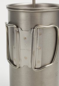 French press en acier inoxydable avec une finition texturée, dotée d'une poignée métallique et d'un logo de marque visible. Corps arrondi, design minimaliste.