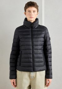 Juodas pūkuotas švarkas, siuvinėjimo dizainas, aukštas apykaklė, užtrauktukas priekyje, šoniniai kišeniai, prigludusi siluetė, tekstūruota medžiaga, minimalus ženklinimas ant rankovės.