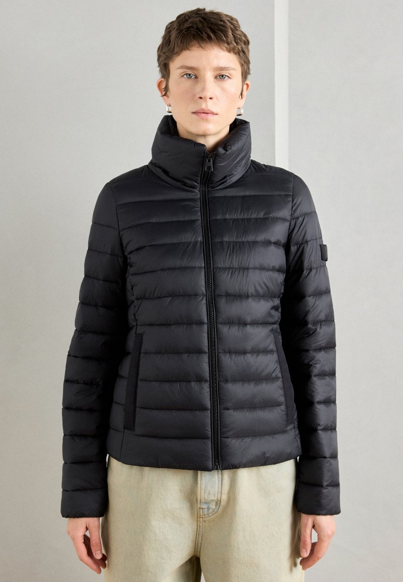 Juodas pūkuotas švarkas, siuvinėjimo dizainas, aukštas apykaklė, užtrauktukas priekyje, šoniniai kišeniai, prigludusi siluetė, tekstūruota medžiaga, minimalus ženklinimas ant rankovės.