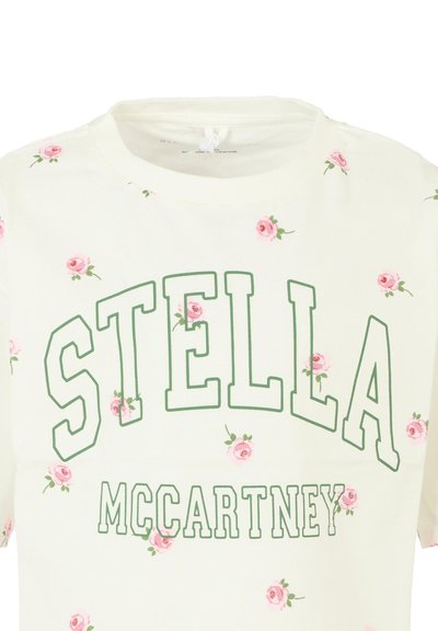 T-shirt di cotone crema con testo verde che recita "STELLA McCARTNEY" e piccoli motivi floreali rosa sparsi. Collo rotondo, maniche corte.