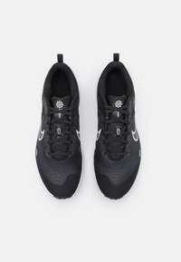 Scarpe sportive nere con tomaia testurizzata, caratterizzate da accenti e lacci bianchi, un'etichetta sul tallone e una soletta imbottita per il comfort.