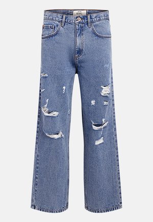 Μπλε τζιν παντελόνι με φαρδιά γραμμή, με πολλές σχισμές και φθορές στα μπροστινά μέρη των μηρών και στα γόνατα, κλείσιμο με κουμπί και φερμουάρ, και θηλιές για ζώνη.