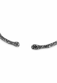 Fascia nera e bianca con un motivo a serpente, caratterizzata da un design liscio e curvo, con una finitura lucida e estremità allungate che ricordano forme di serpente.