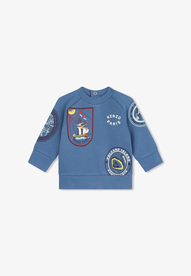 Sweatshirt bleu orné de patchs brodés, incluant des designs de navire et de volcan. Les poignets et l'ourlet côtelés apportent une finition texturée.