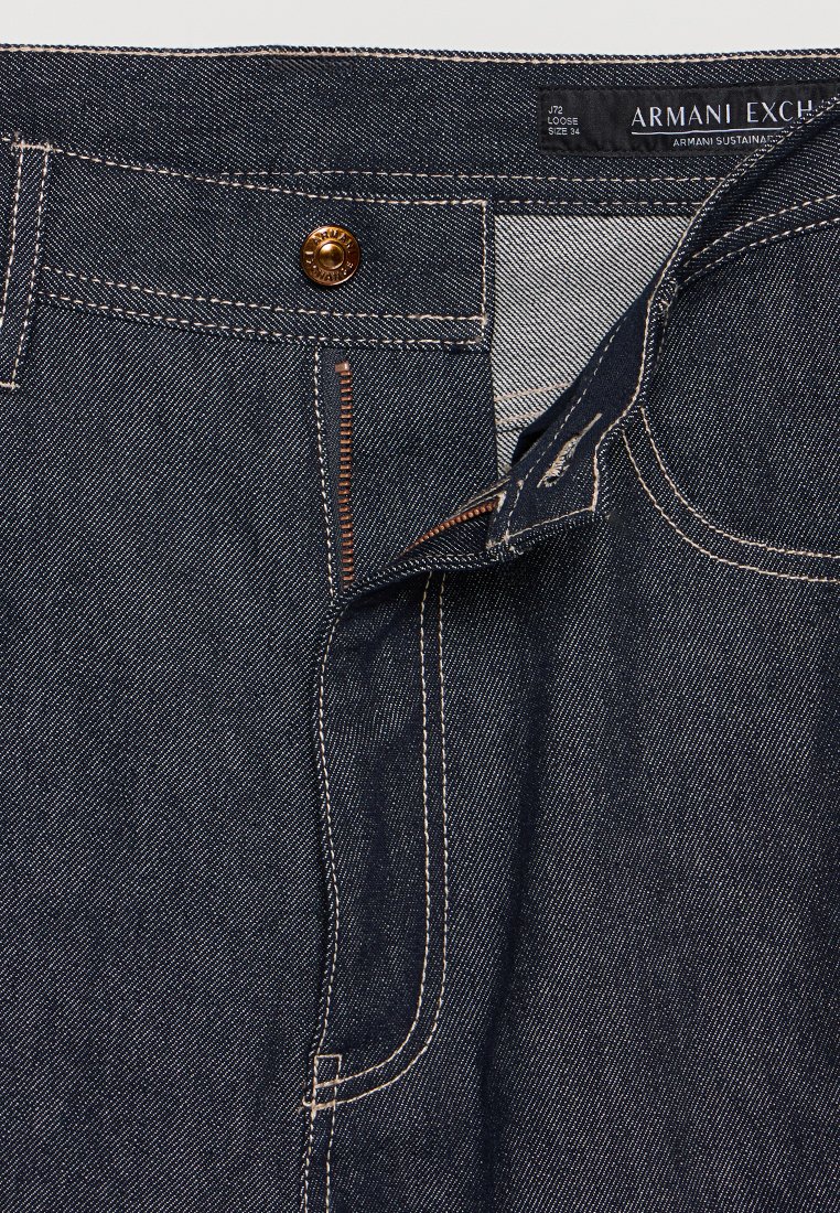 Dunkelblaue Denim-Jeans mit lockerer Passform, ausgestattet mit einem Metallknopf, Reißverschluss und kontrastierenden orangen Nähten. Label sichtbar: Armani Exchange.