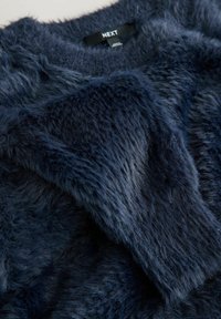 Maglione di pelliccia blu navy con una superficie strutturata e morbida. Presenta un collo rotondo e maniche lunghe, con diverse lunghezze di pelliccia.