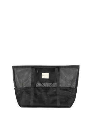 Bolso tote grande de malla negra con dos asas y una etiqueta blanca que dice "Ysabel Mora" sobre un fondo liso.