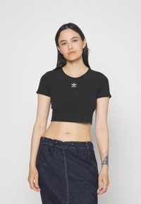 Must tee-shirt, mis on tehtud puuvillast, lühikeste varrukatega ja ümmarguse kaelusega, esiküljel on väike valge Adidas'i logo.