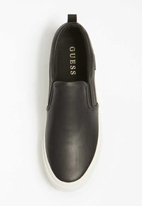 Černá kožená slip-on bota s bílou gumovou podrážkou. Má hladký povrch a elastické boční panely. Logo "GUESS" viditelné uvnitř.