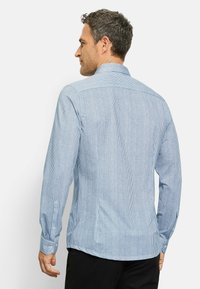 Langarmhemd mit blauen und weißen Streifen, mit kragenlosem Ausschnitt, Knopfmanschetten und einem Rückenpasse-Detail, aus gewebtem Stoff hergestellt.