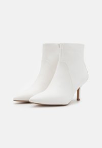Weiße Ankle Boots mit einer spitzen Zehe, glattem Lederanteil, schlankem Stiletto-Absatz und einem nahtlosen Design ohne sichtbare Verschlüsse.