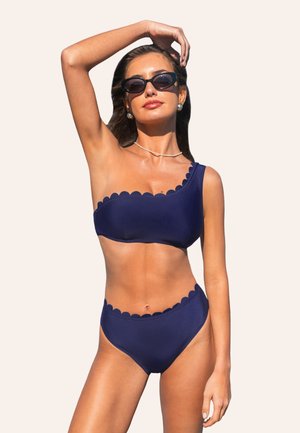 Conjunto de bikini azul marino hecho de una tela suave; top de un solo hombro con bordes en forma de concha, parte inferior de cintura alta con detalles a juego en forma de concha.