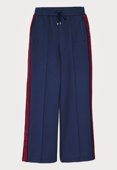 Pantalones de chándal navy con rayas rojas en los laterales, hechos de una tela suave. Tienen una cintura elástica con cordón y bolsillos laterales. Diseño de pierna ancha.