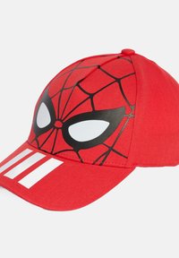 Gorra roja con un diseño de Spider-Man que presenta patrones de telaraña negra y grandes ojos blancos. En la parte frontal, incluye tres rayas blancas en la visera.