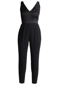 Combinaison noire sans manches avec un col en V profond, taille cintrée avec une bande scintillante et pantalon fuselé longueur totale.