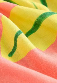 Tissu en coton avec un fond jaune vif, présentant des lignes vertes ondulées et des sections rose corail, affichant une texture douce et lisse.
