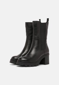 Czarne skórzane botki na kostkę z grubym obcasem, elastycznymi bocznymi panelami i teksturowanym wykończeniem. Posiadają solidną gumową podeszwę zapewniającą przyczepność.